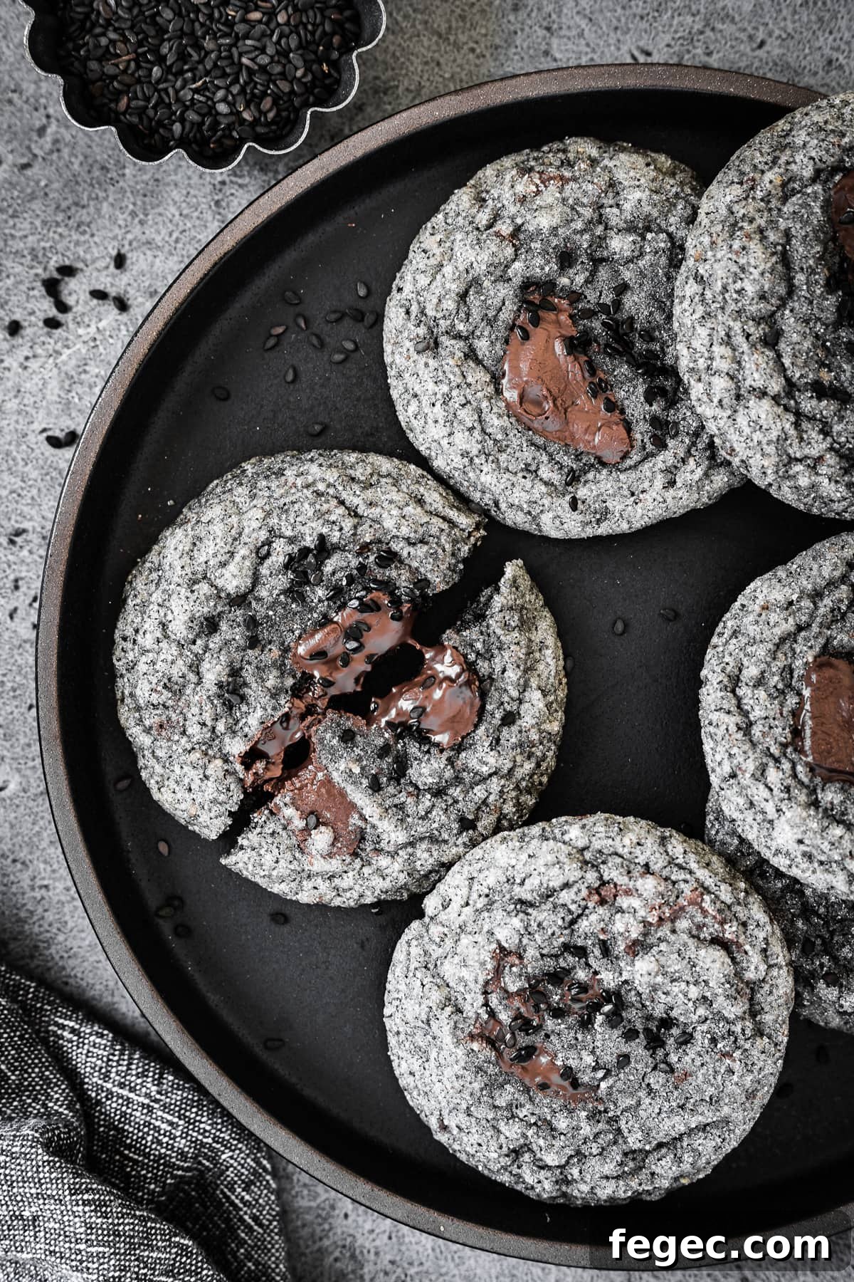 A closeup photo of cookies on a black plate, resting on a grey stone surface.