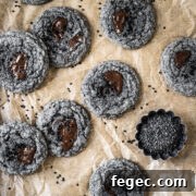 Black sesame cookies with pools of melted chocolate on a brown parchment paper background.