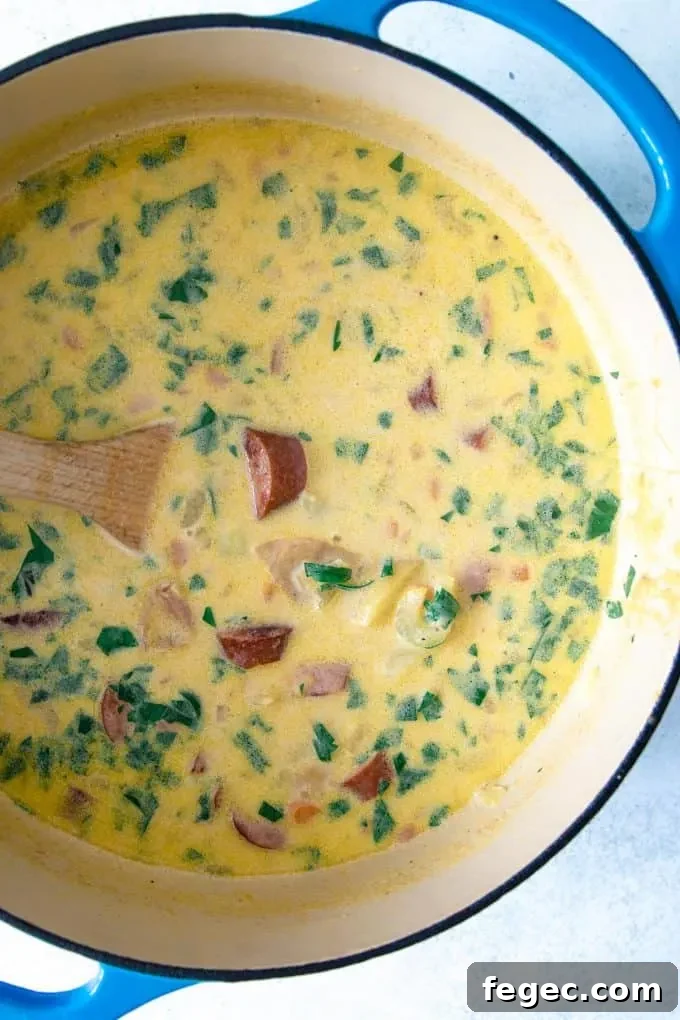 potato kielbasa soup in a dutch oven with a wooden spoon