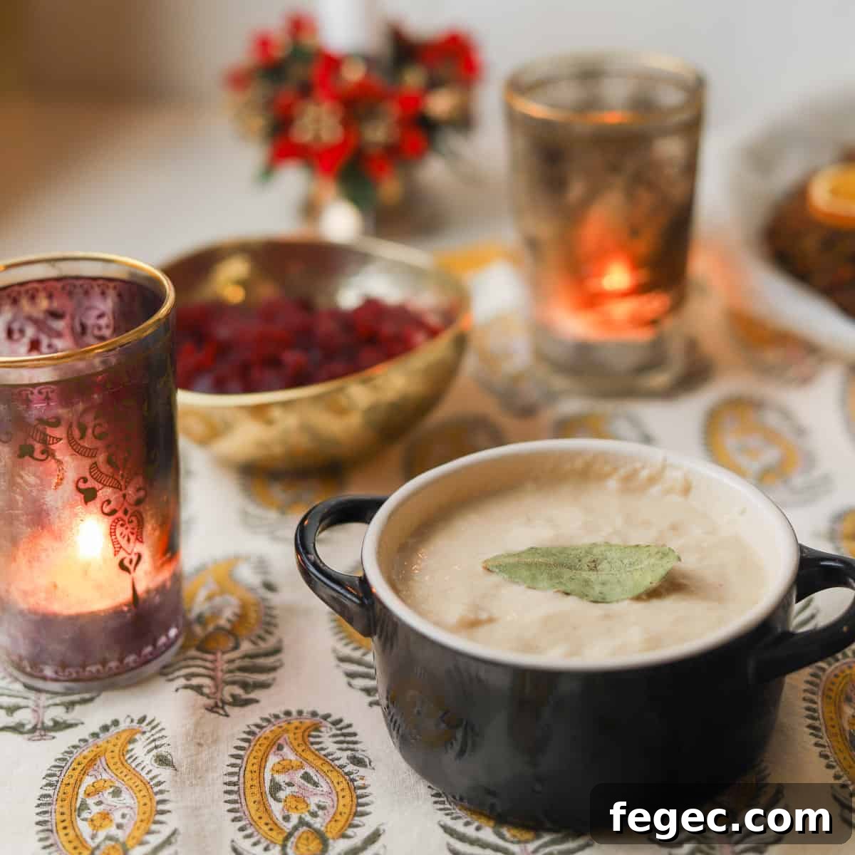 Photo of a dish of bread sauce on a set table with candles and cranberry sauce in the background and a nut roast at the back.