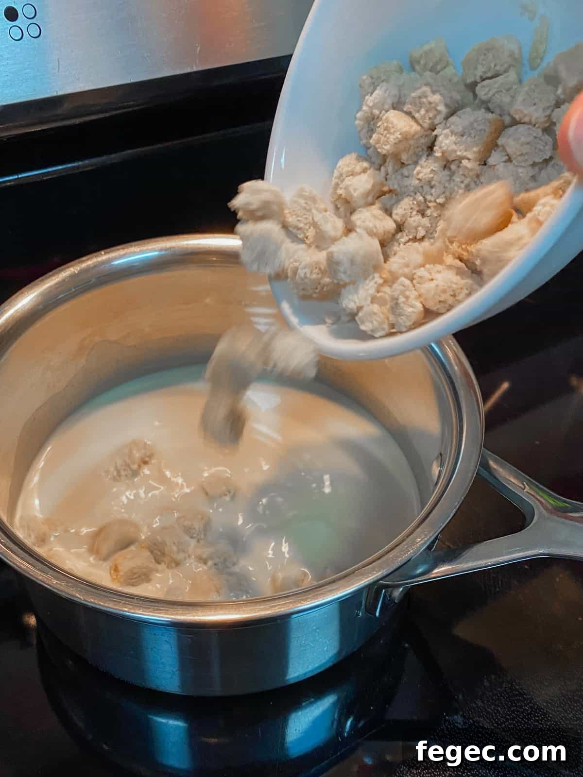 Photo of milk in the pan and adding GF bread cubes to the pan.