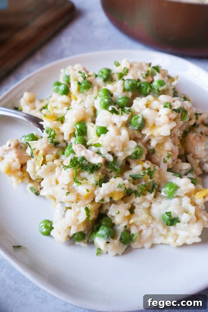 plate with risotto topped with chicken, peas, and parsley.