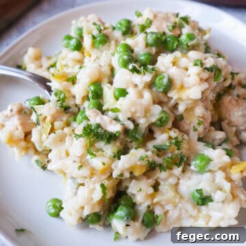 plate with risotto topped with chicken, peas, and parsley