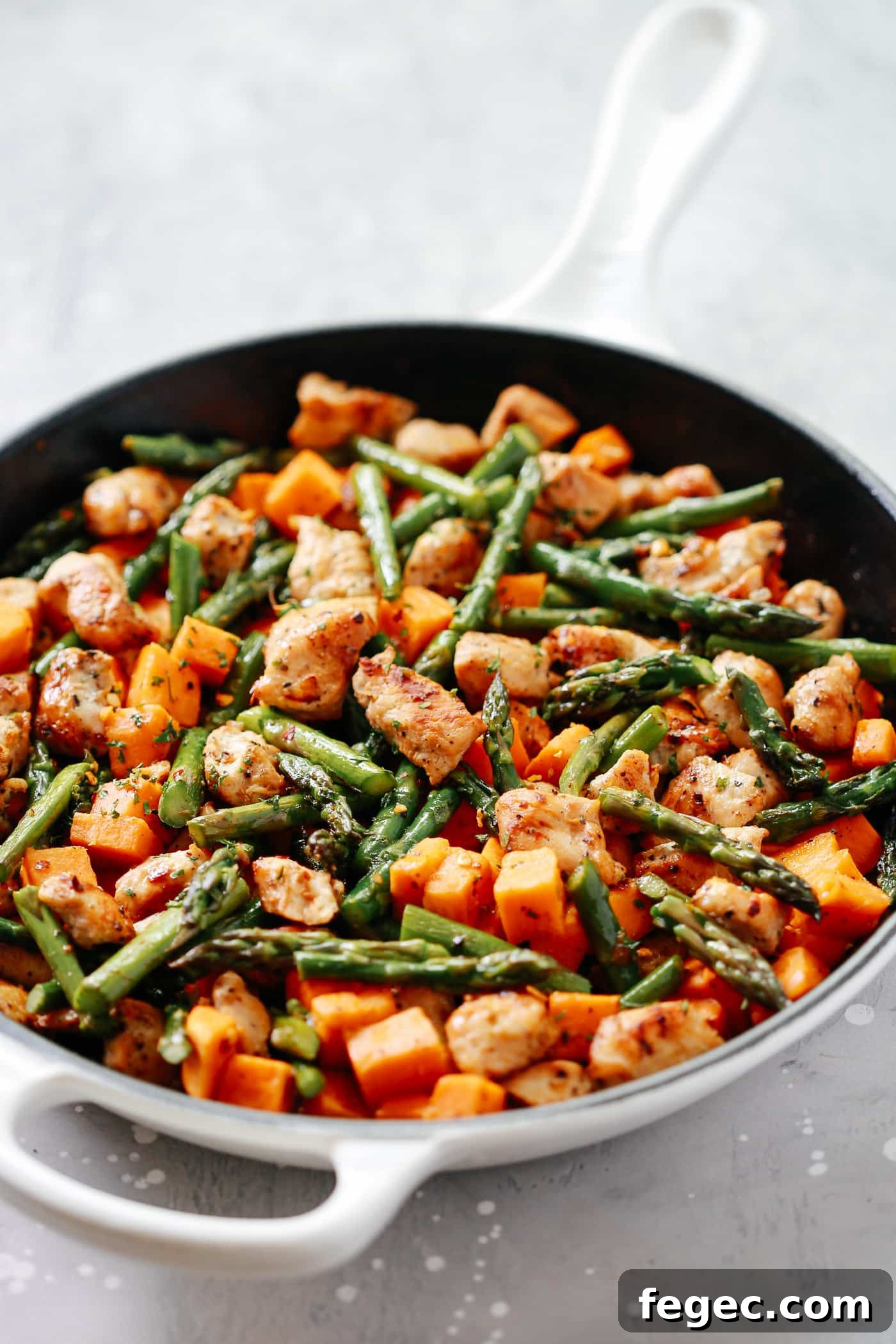 A closeup of chicken sweet potato recipe in a cast iron skillet.