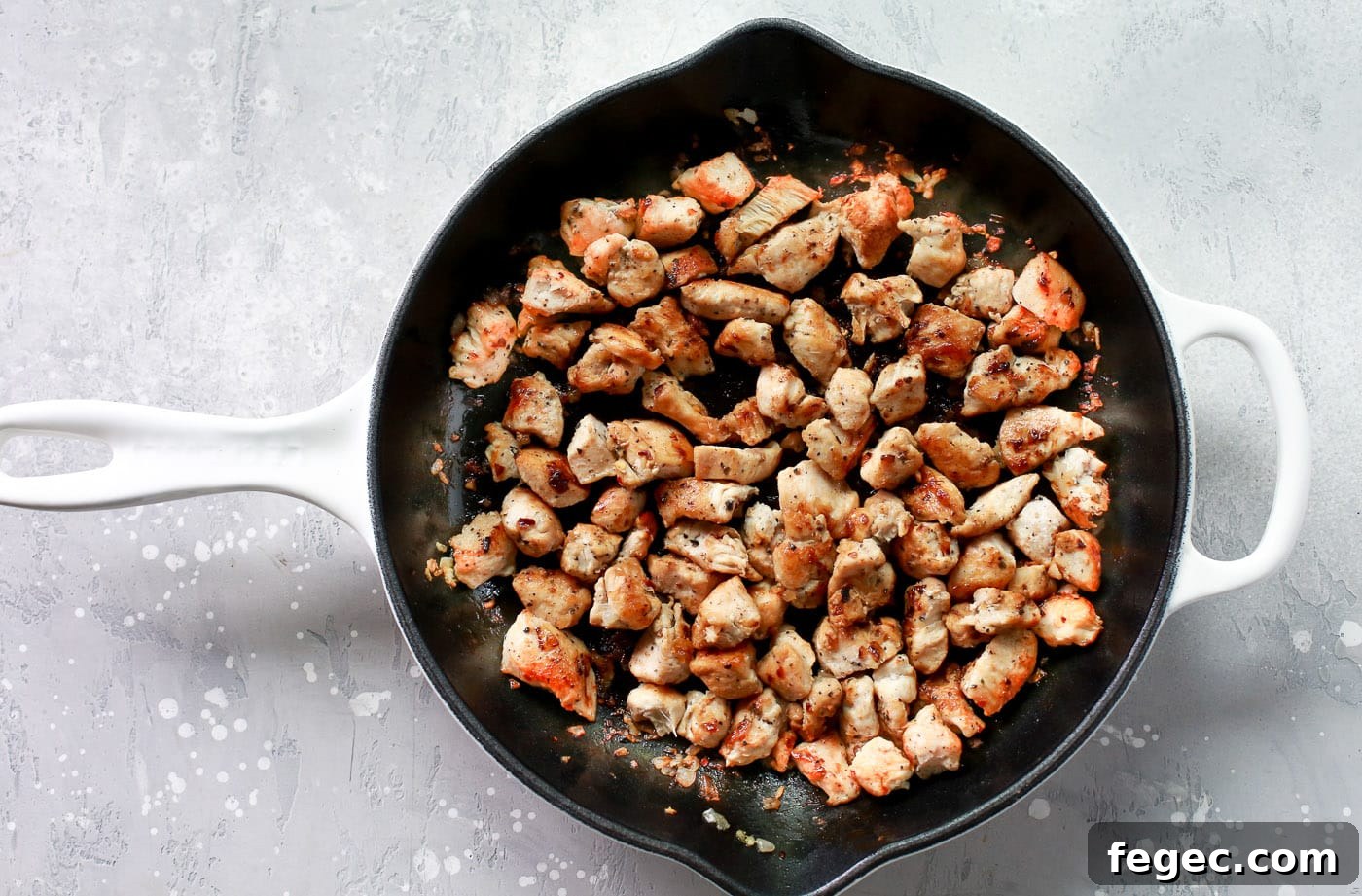 Pieces of chicken cooking in a skillet.