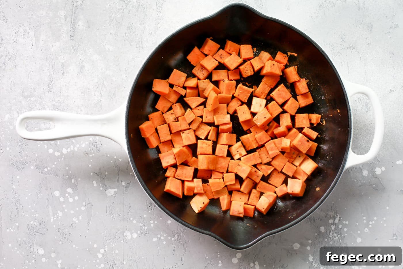 Diced sweet potatoes cooking in a skillet.
