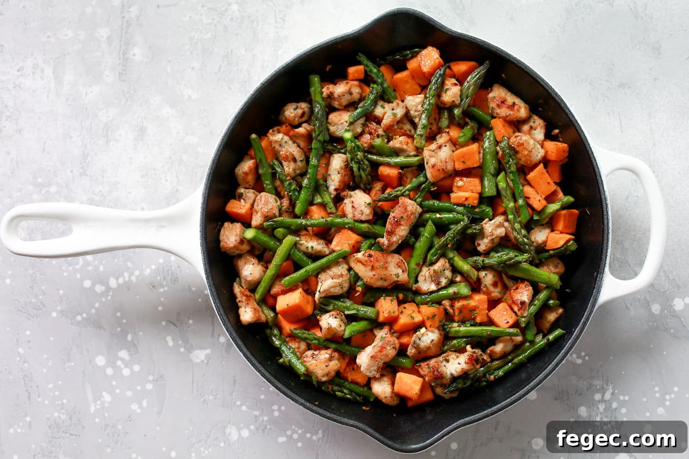 Chicken, sweet potatoes, and asparagus in a skillet.