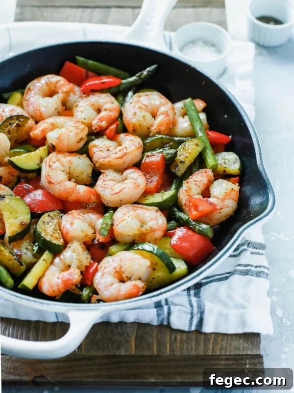 A white cast iron with shrimp and vegetables inside.