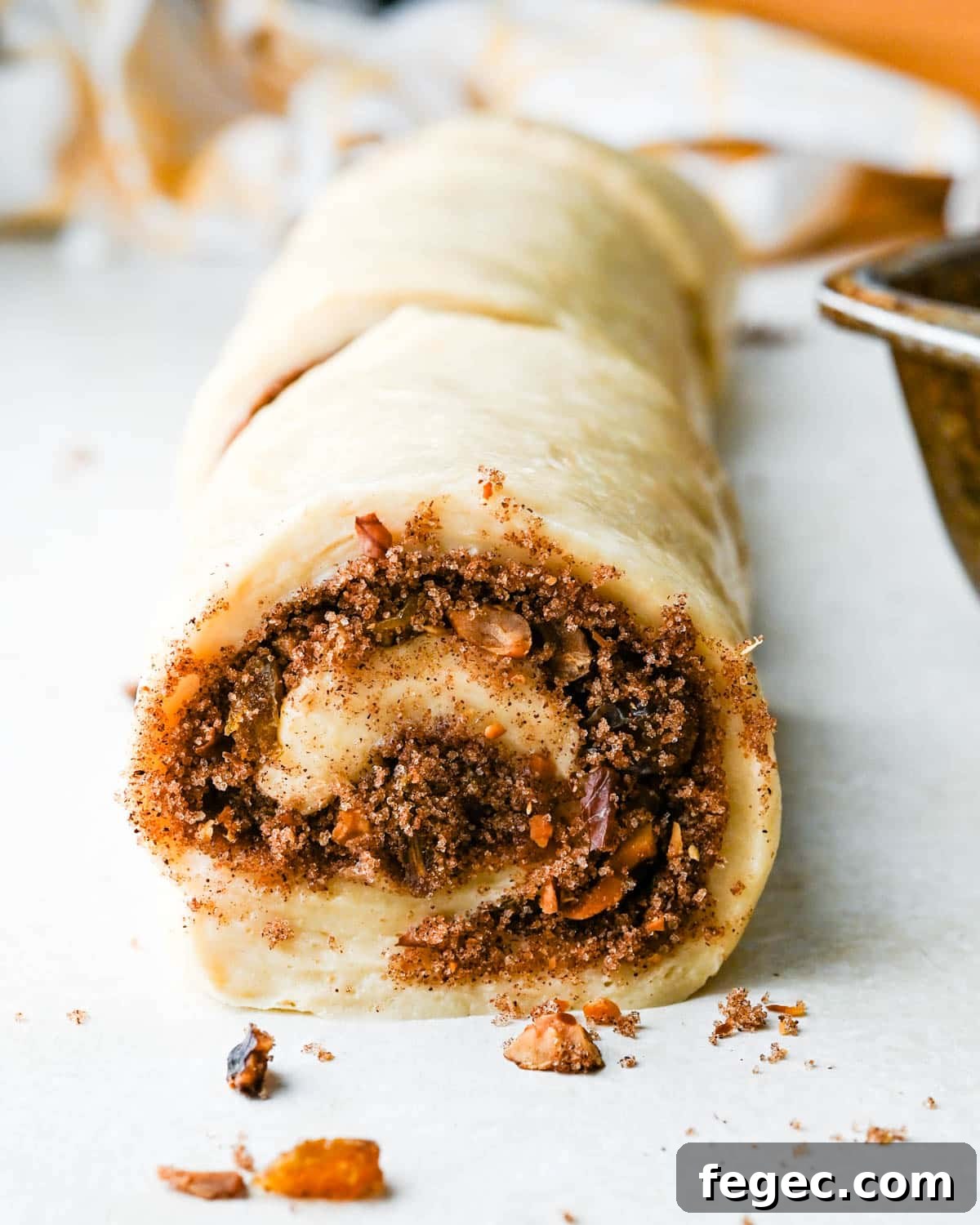 Rolling the cinnamon raisin rolls into a cylinder. 