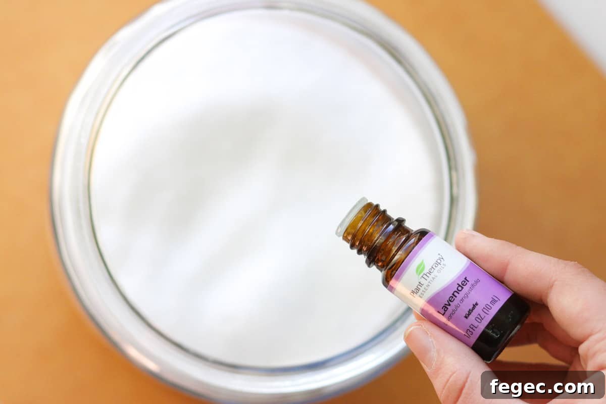 DIY Natural Laundry Scent Booster: Homemade Recipe & Guide 4 lavender essential oil being added to a glass jar of baking soda mixed with Epsom salts