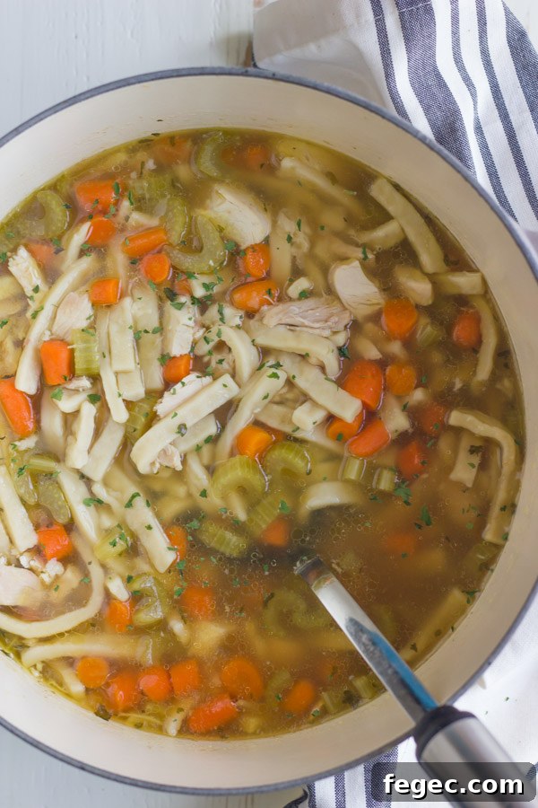 Homemade Chicken Noodle Soup in a large pot with a serving spoon.  