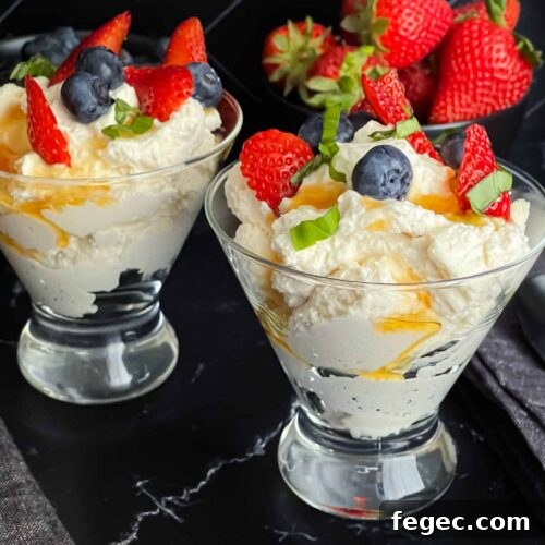 Ricotta mousse in a stemless martini glass garnished with strawberries, blueberries, basil, and honey.