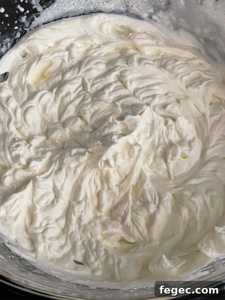 Whipped heavy cream in a glass mixing bowl.