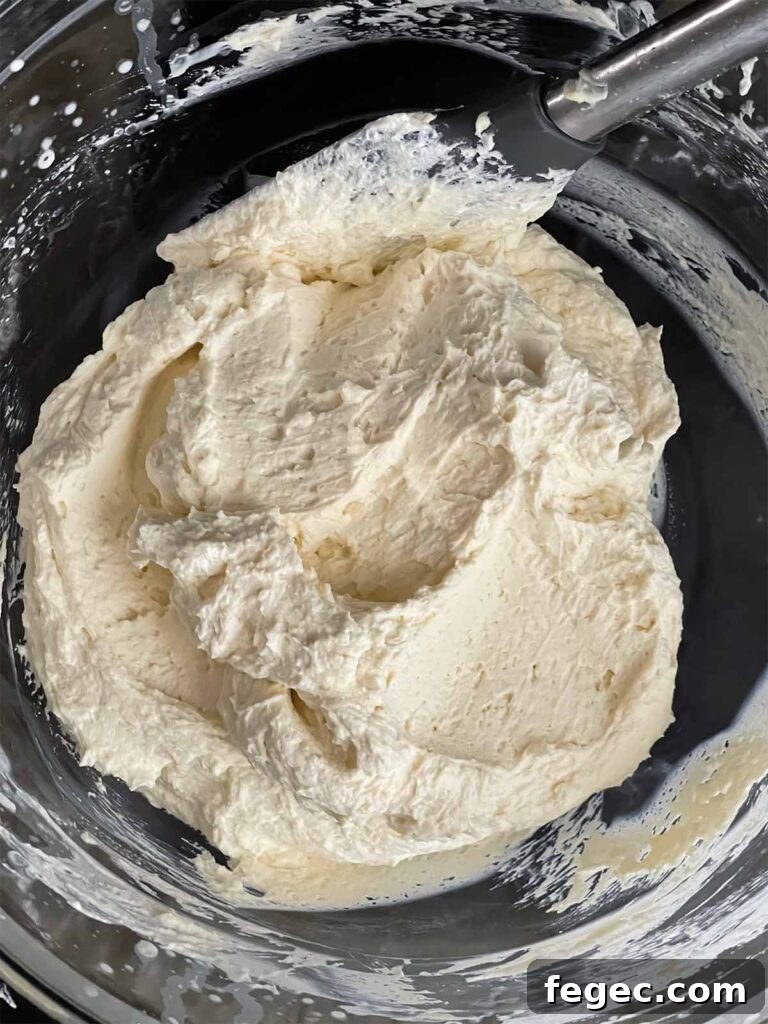 Ricotta mixture folded into the whipped cream in a glass mixing bowl.