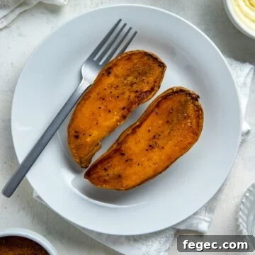 Two roasted sweet potato halves on a round white plate with a fork.