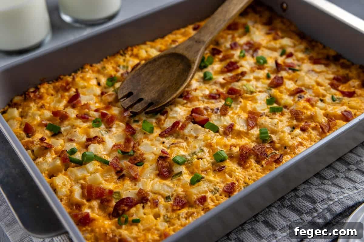 Cheesy Loaded Hash Brown Casserole with Bacon and Green Onions 7 Baked hashbrown casserole in the casserole dish with wooden serving spoon resting on top.