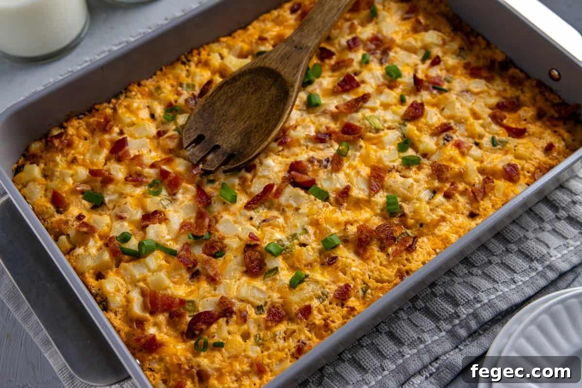 Cheesy Loaded Hash Brown Casserole with Bacon and Green Onions 8 Baked potato casserole in the casserole dish with wooden serving spoon resting on top.