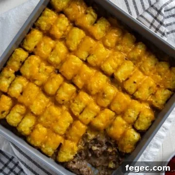 Baked casserole in square metal pan with scoop removed from corner.