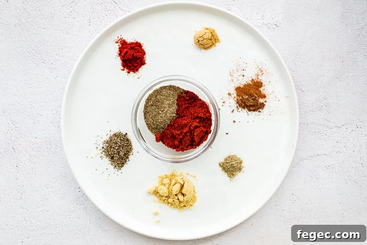 Ground ingredients for an easy Old Bay substitute are arranged on a white plate and placed on a concrete surface.