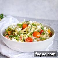 white bowl with zucchini noodle pasta toped with tomatoes and fresh herbs