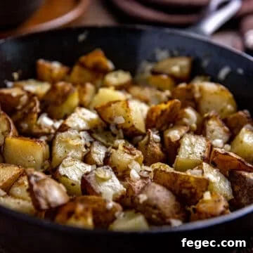 crispy fried sliced potatoes and bits of onion and garlic in a cast iron skillet