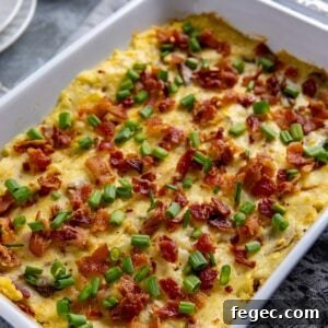 White casserole dish filled with baked mashed potatoes. Garnished with cooked crumbled bacon and sliced green onions.