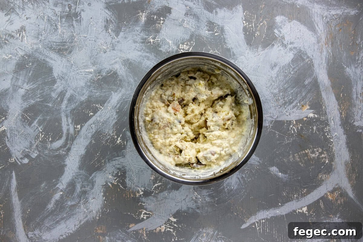 Roasted and mashed potatoes in a bowl mashed with butter, sour cream, salt, and pepper.