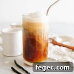 vanilla sweet cream cold brew in a clear glass with vanilla cold foam and a metal straw.