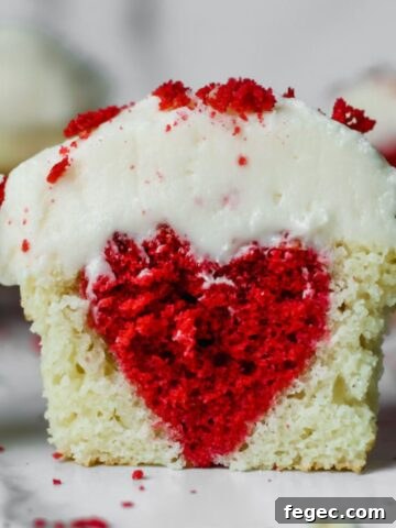 A cupcake sliced in half with a red heart baked inside.