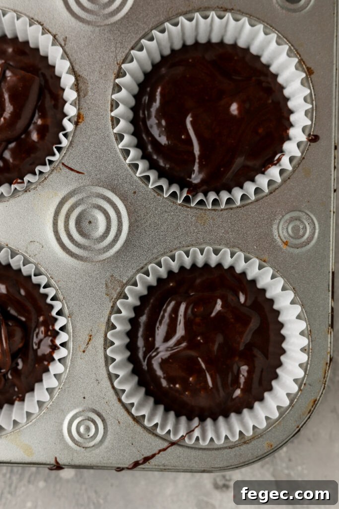 A cupcake pan with paper liners filled with chocolate cupcakes. 