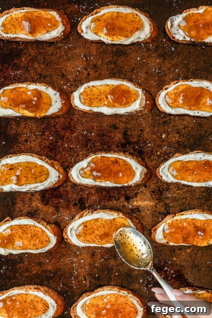 Fig & Goat Cheese Crostini with Honey Drizzle 8 A hand spreading fig jam on toasts.
