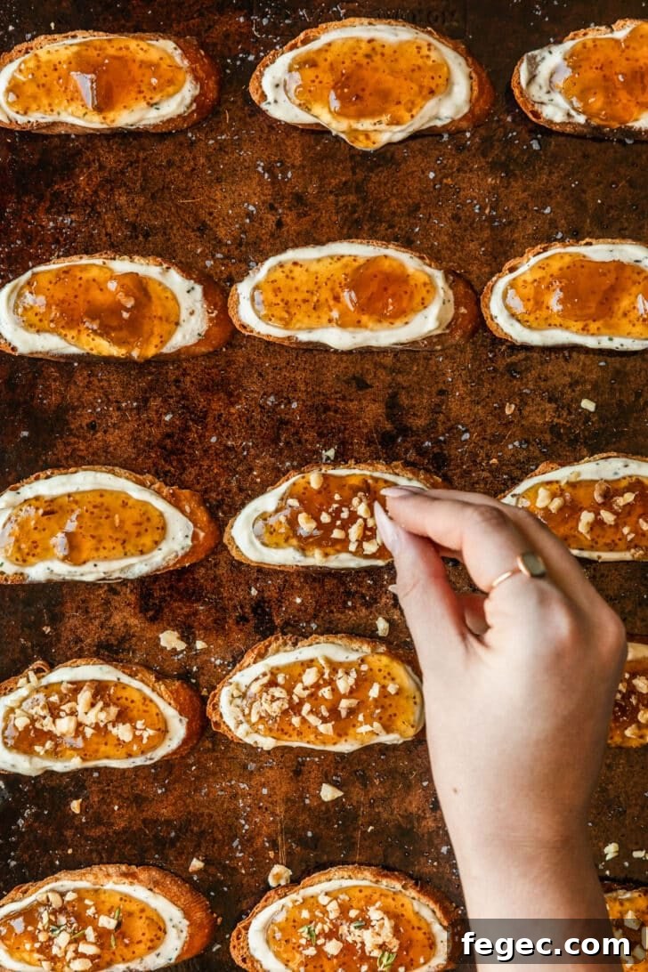 Fig & Goat Cheese Crostini with Honey Drizzle 9 A hand sprinkling walnuts on crostini.