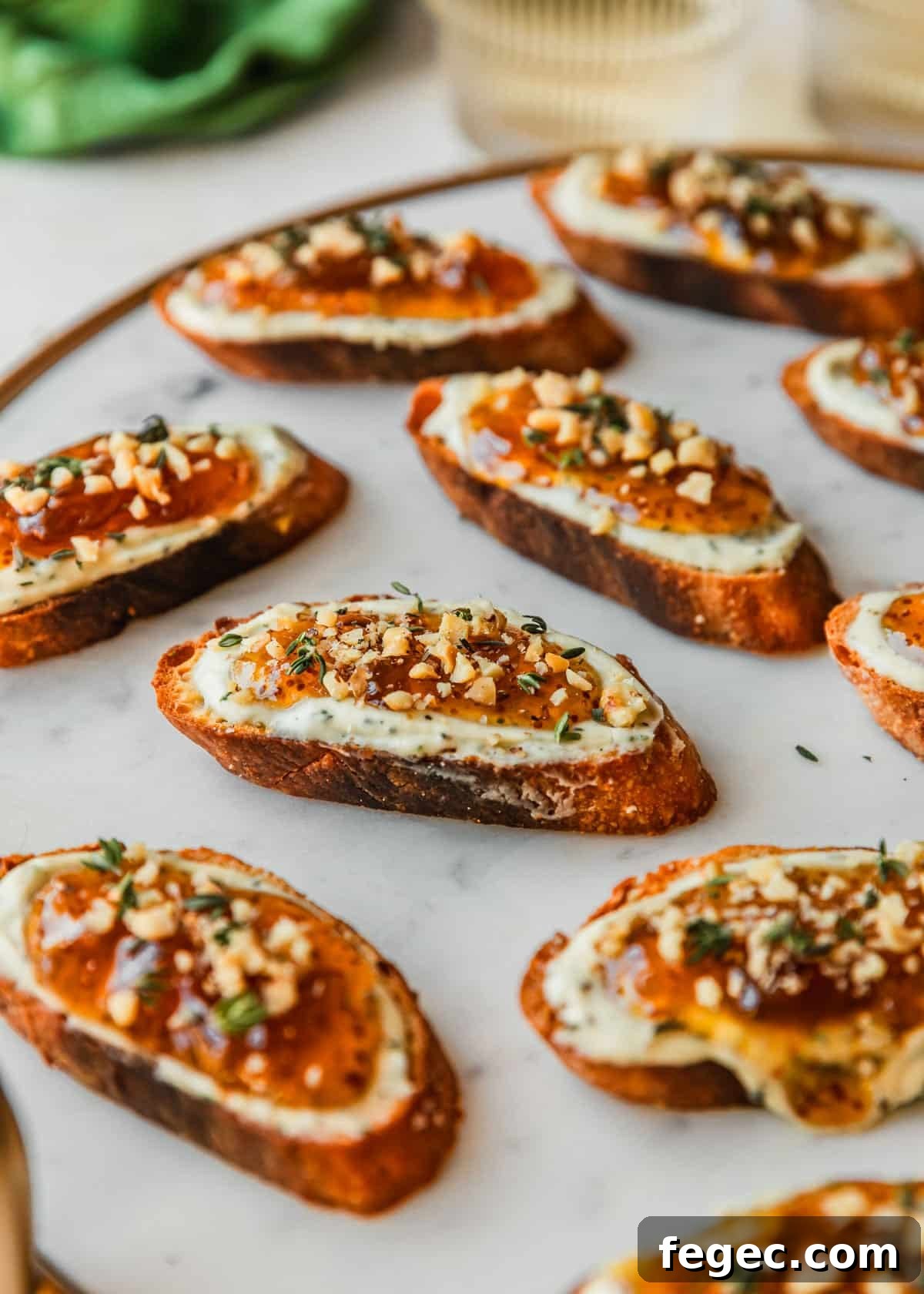 Fig & Goat Cheese Crostini with Honey Drizzle 10 Fig goat cheese crostini on a marble board next to white wine and a green linen.