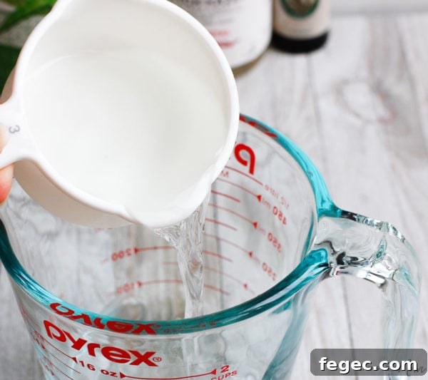 pouring ingredients into glass measuring cup for DIY face toner recipe