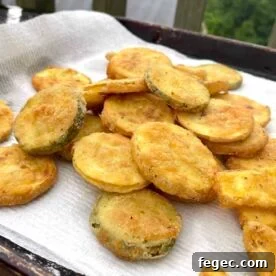 Fried squash slices draining on a paper towel.