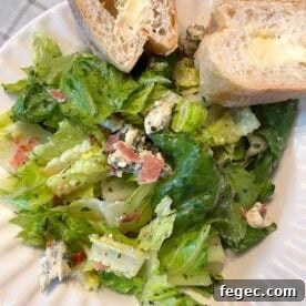 A bowl of royal street salad and two slices of buttered french bread.