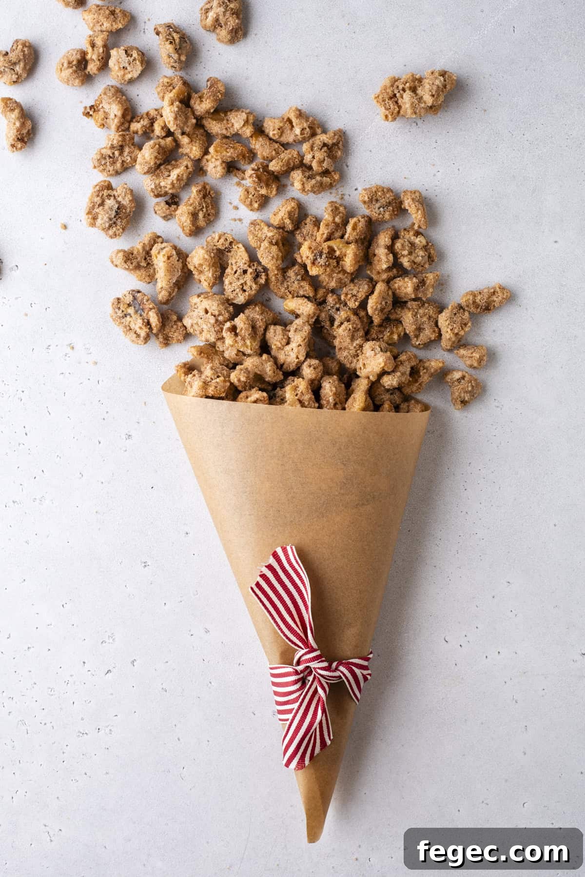 candied walnuts spilling out of a brown paper cone with a red and white striped ribbon tied around it