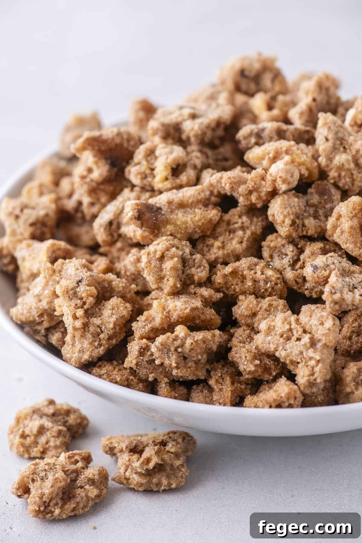 candied walnuts in a white bowl, with three more outside the bowl