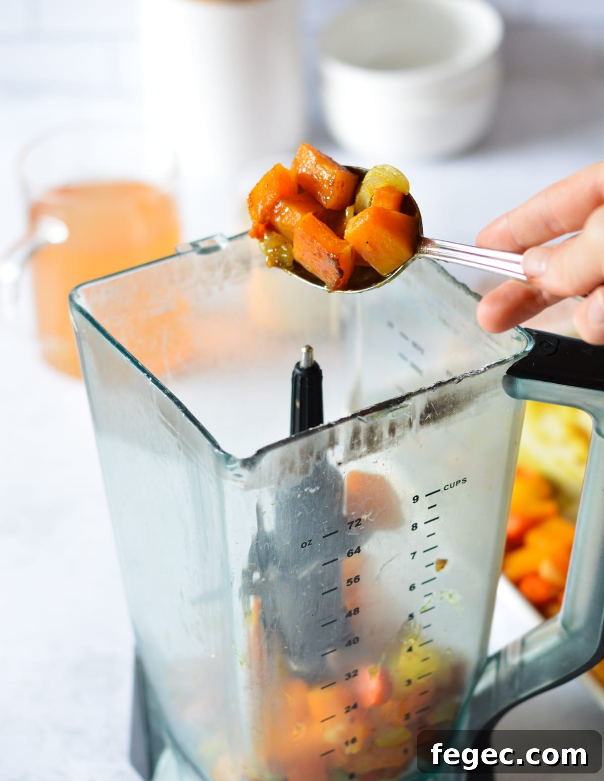 Creamy Roasted Butternut Squash Soup with Sage and Brown Butter 9 hand scooping roasted squash and dumping it into a blender.