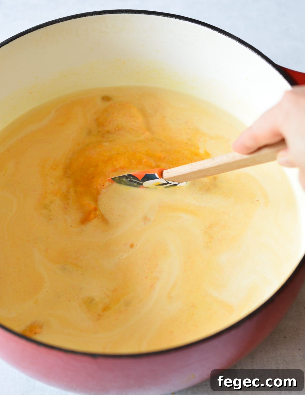Creamy Roasted Butternut Squash Soup with Sage and Brown Butter 11 stirring cream into butternut squash soup with a spatula.