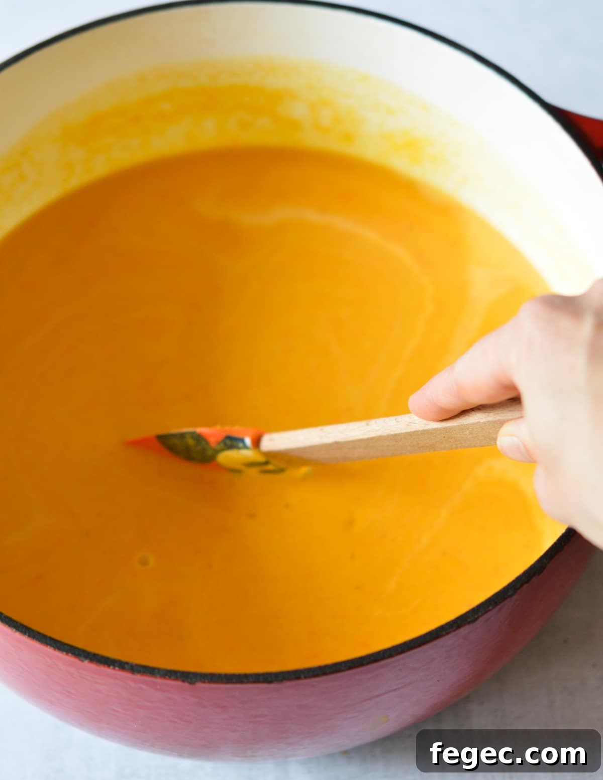 Creamy Roasted Butternut Squash Soup with Sage and Brown Butter 12 stirring butternut squash soup in a large dutch oven.