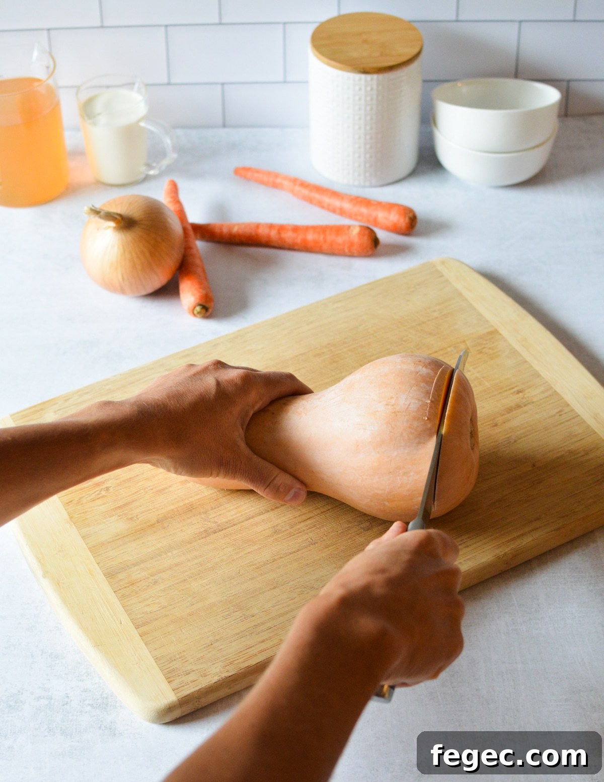 Creamy Roasted Butternut Squash Soup with Sage and Brown Butter 4 hand cutting the end off a butternut squash.