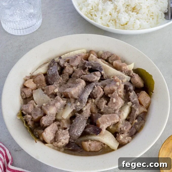 Kilawing Labanos at Baboy in a white serving bowl with a plate of rice in the background.