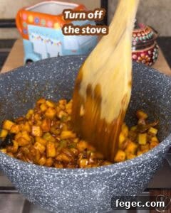Traditional Kerala style mango pickle being cooked in a pan with spices.