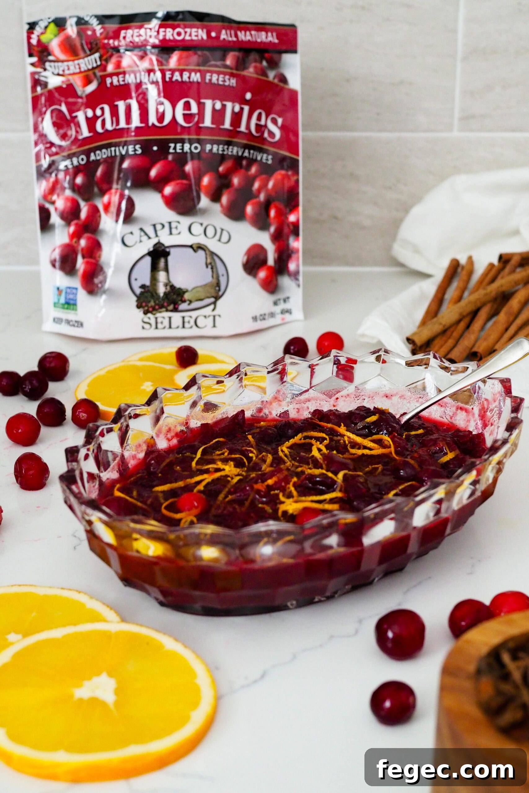 A Cape Cod Select frozen cranberries bag in the background of a crystal dish full of cranberry orange sauce.