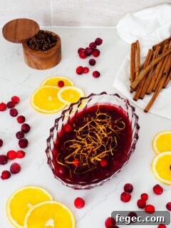 Cranberry orange sauce on a quartz counter with orange slices and cranberries around it.