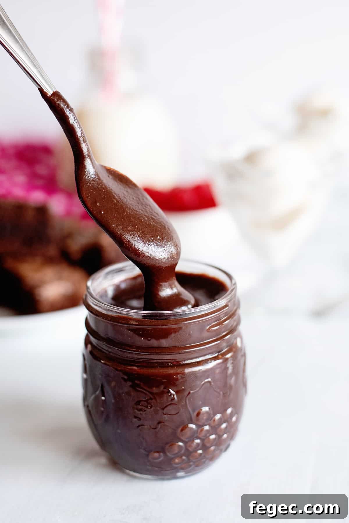 a spoon dipping into a jar of homemade hot fudge