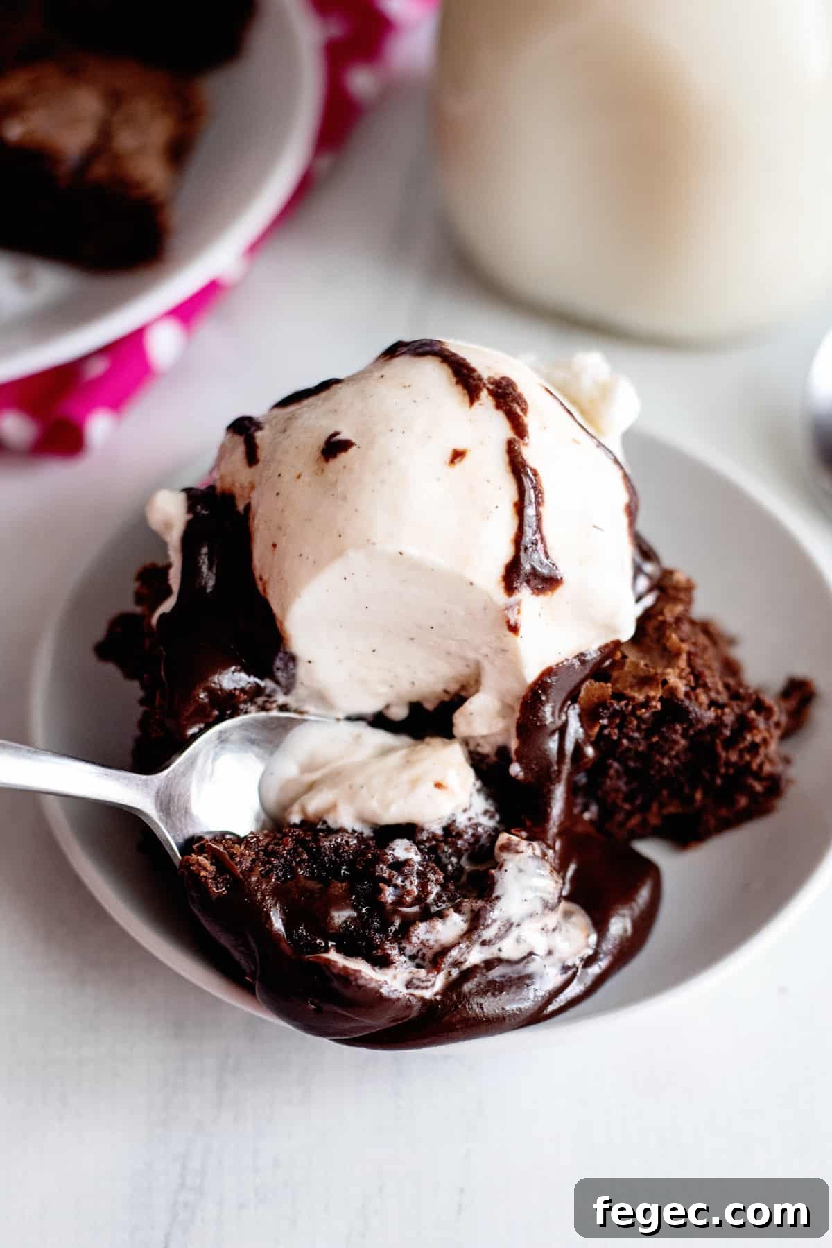 spoon scooping up a piece of brownie with ice cream and hot fudge