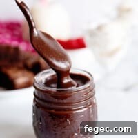 a spoon dipping into a jar of homemade hot fudge