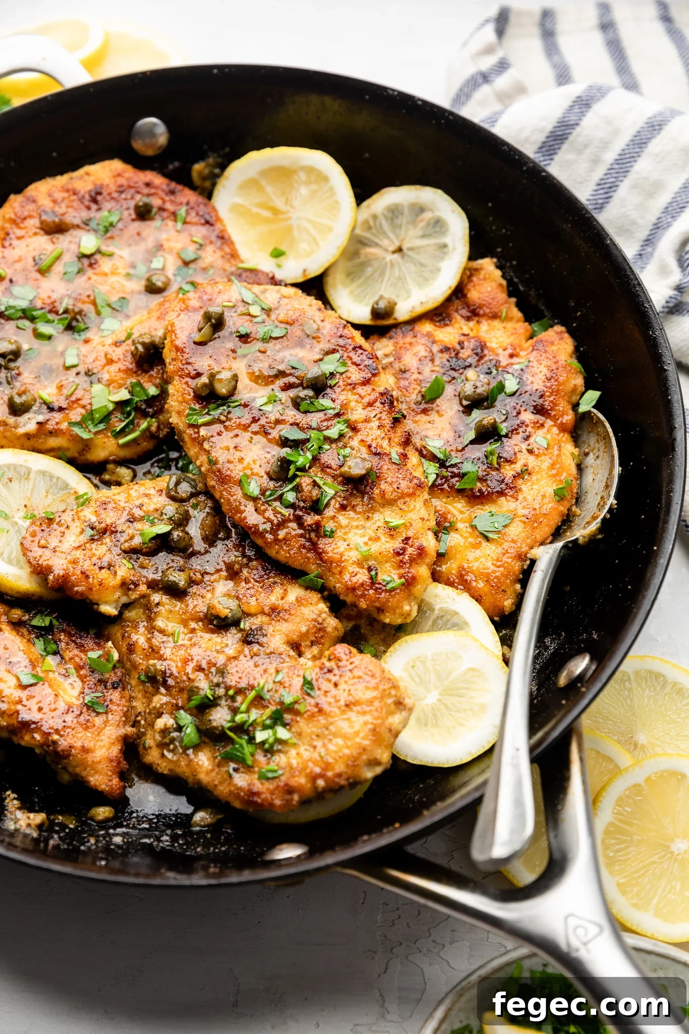 Gluten-Free Chicken Piccata with Lemon Caper Sauce 2 chicken piccata with capers and lemon slices in a skillet with a silver spoon